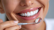 © master1305 - Close-up smiling woman with bright clean teeth holding dental mirror with joyful emotion. Concept of dental care education, clinic promotion, and hygiene product visuals.