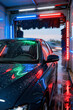 © yuliachupina - Bright lights highlight a car being washed at a detailing station in a modern facility amidst a rainy day