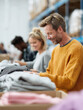 © SolaruS - Diverse team sorting donations in a warehouse. Engaged workers organizing clothing. Could symbolize charity, community, volunteerism, or ethical business practices.
