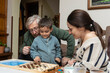 © Sylvie Pabion Martín - Warm Family Moment: A Grandfather, Mother, and Son Joyfully Playing a Board Game Together