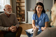 © Goran - Female doctor holding hands with her patient during home visit.