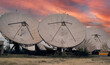 © ivan canavera - Large satellite dishes facing sunset sky in a telecommunications facility