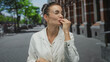 © Krakenimages.com - Woman with hands open blowing kisses on a city street wearing a white coat and clear glasses; playful affection.