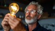 © iuricazac - Man holding light bulb, working at workbench.