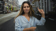 © Krakenimages.com - Woman points finger to the right on a cobblestone street in a city, blue shirt and yellow nails visible; confidence urban.