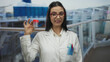 © Krakenimages.com - Young hispanic woman scientist in a uniform holds a test tube on a cruise ship deck outdoors expressing curiosity and focus on science at sea.