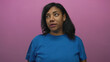 © Krakenimages.com - African american woman grimaces in studio with purple backdrop wearing blue shirt and loose hair under soft lighting; disgust.