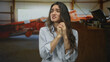 © Krakenimages.com - Young hispanic woman clasping hands near chest in studio with tense expression; fear vulnerability.