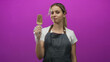 © Krakenimages.com - Woman holding chocolate coated popsicle with gloved hand in studio with magenta backdrop and denim apron; contentment.