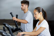 © auremar - man and woman walking on treadmills in modern gym