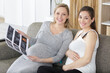 © auremar - two pregnant women looking at print out of ultrasound scan