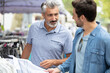 © auremar - two men looking at clothing in a street market