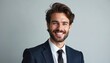 © Viktor - Young smiling brunette businessman in dark blue suit and tie poses for portrait. Male executive with beard looks confident, ready for pro photo session. He represents success and modern leadership.