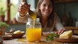 © Viktor - Woman happily pours golden ghee into jar for cooking. Homemade dairy clarified butter oil for healthy meal prep in kitchen. Natural food ingredient for tasty dish.
