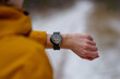 © Alina Mosinyan - Close-up of an athlete checking heart rate on a smartwatch during a winter workout. The digital screen displays 129 bpm and Zone 2 intensity. Person wears a yellow jacket, snowy outdoor environment