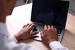 © New Africa - African-american man using laptop at wooden table indoors, closeup