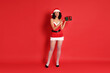 © New Africa - Beautiful woman in Mrs Claus costume with Christmas gift on red background