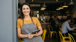 © Andrew505 - Proud entrepreneur and successful small business owner standing at her modern coffee shop entrance with a digital tablet.