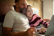 © Geber86 - Mature father and teen smiling while online shopping on laptop at home