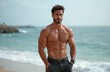 © Viktor - Muscular topless man stands on a beach. He wears shorts and watch. Model poses showing strong body. Ocean waves on background. Handsome fit guy at seaside.