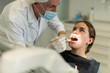 © JackF - During reception, dental practice, mature male dentist doctor diagnoses teeth of patients girl, examines condition of oral cavity, gums, teeth. Doctor looking for bad tooth and source of pain