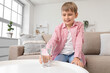 © Pixel-Shot - Cute little boy taking glass of water in living room
