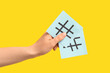 © Pixel-Shot - Female hand holding sticky notes with hashtags on yellow background