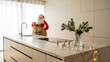 © peppystudio - Christmas scene with Santa Claus and gift bag on white marble kitchen island, modern Scandinavian interior, pine branches and warm lights, winter holiday, concept of festive home