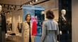 © MdRifat - Woman trying on virtual red dress with smart mirror in fashion boutique