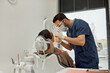 © Seventyfour - Young adult male dentist examining mature Caucasian woman sitting in dental chair during dental appointment, dentist wearing protective mask and gloves, dental equipment visible