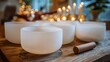 © mila103 - Set in a cozy indoor space several frosted singing bowls sit on a rustic wooden table. Flickering candlelight adds warmth creating a peaceful atmosphere for relaxation or meditation.