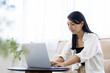 © hidez - Young Woman Working from Home While Talking on Smartphone