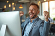 © Maryna - Happy businessman celebrates win at office. Male employee excited with fist in air near computer monitor. Successful man in suit achieves goal at workplace. Joyful person proud of promotion success.