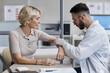 © Seventyfour - Caucasian middle aged woman consulting male dermatologist examining skin on forearm during medical appointment in clinic setting, both focused on dermatological assessment process
