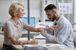 © Seventyfour - Caucasian middle aged woman sitting while male dermatologist examining her arm with magnifying glass during medical consultation in clinic, both focused on skin assessment