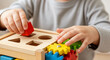 © oliamogdaleva - Child’s hands playing with wooden shape sorter and gear toy. Development of motor and cognitive skills.