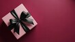 © Ali Raza - Elegant pink gift box with a luxurious black satin ribbon and bow presented on a deep burgundy background perfect for celebrations and special occasions