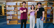 © Raushan_films - Indian happy young adult gen z male man group standing indoor library look camera spend break time. Asian boy girl great team show thumbs up hand sign staring cam do casual pose enjoy fun joy day