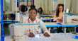 © Raushan_films - African young adult gen z lady female wear tape around neck look cam indoor class room learn good craft skill sewing machine happy teen girl pupil staring camera do casual pose new college day place