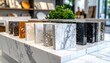 © CreativeCreations - Collection of natural stone samples including granite, marble, and quartz for kitchen counters showcased on a white marble base inside a stone countertop store
