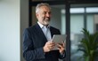 © ye - happy middle aged business man ceo wearing suit standing in office using digital tablet smiling mature businessman professional executive manager looking away thinking working .stock photo