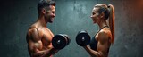 Athletic man and woman lift dumbbells, train together. Fitness concept shows muscle workout. Couple smiles, enjoys health, fitness training in gym. Fit couple work out with weights together.