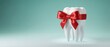 © Yassine - White tooth model wrapped with a festive red ribbon as a gift concept