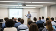 © Morad - Attentive diverse audience in a blurred conference room focused on a male presenter speaking in front of a projection screen.