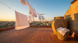 © Video80X - Rooftop scene at sunset featuring white laundry on a line, a clay pot, and a basket of clothes overlooking a city skyline. Ideal for tranquility and home themes.