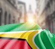 © Muhammad Arif - Guyana flag fluttering on blur street with building. Guyana national flag for independence day.