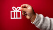 © Olha Havelia - Close-up of a child's hand holding a white cut-out gift isolated against a solid red background with no shadows. The gift with its ribbon is also a white cut-out. No shadows.