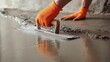 © TensorSpark - Worker leveling wet concrete floor with trowel and wearing orange glove, symbolizing concrete leveling floor repair and surface finishing.