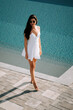 © Darius - Woman in white dress enjoying sunny day by the poolside in a tranquil setting