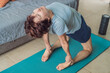© galitskaya - Elderly woman practicing yoga in her cozy living room, stretching on a mat and maintaining balance. Concept of healthy aging, active senior lifestyle, mindfulness, wellness, and daily home exercise